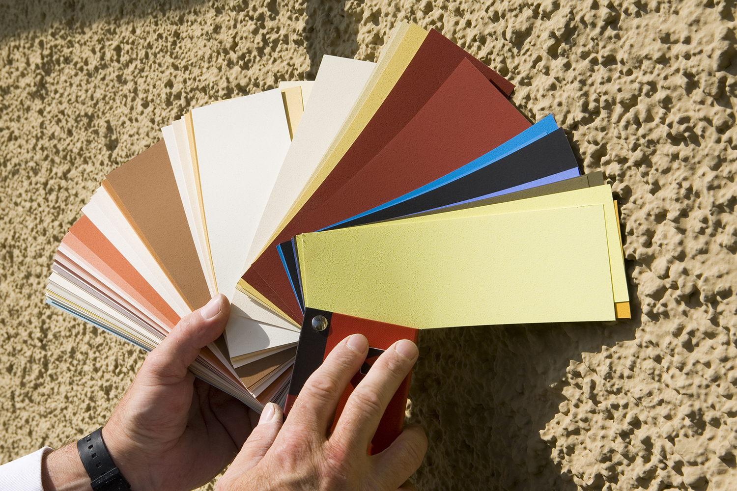 Farbfächerkarte vor strukturierter Putzfassade – professionelle Fassadenfarbberatung mit Echtmustern durch den Malerfachbetrieb Binder.