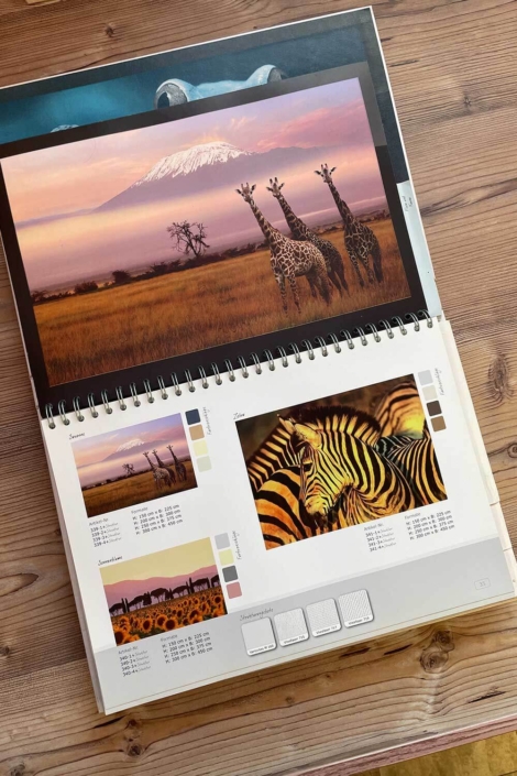 Aufgeschlagenes Inspirationsbuch im Showroom des Malerfachbetriebs Binder mit Naturmotiven, Tierfotografien und Farbmustern für Wandgestaltung