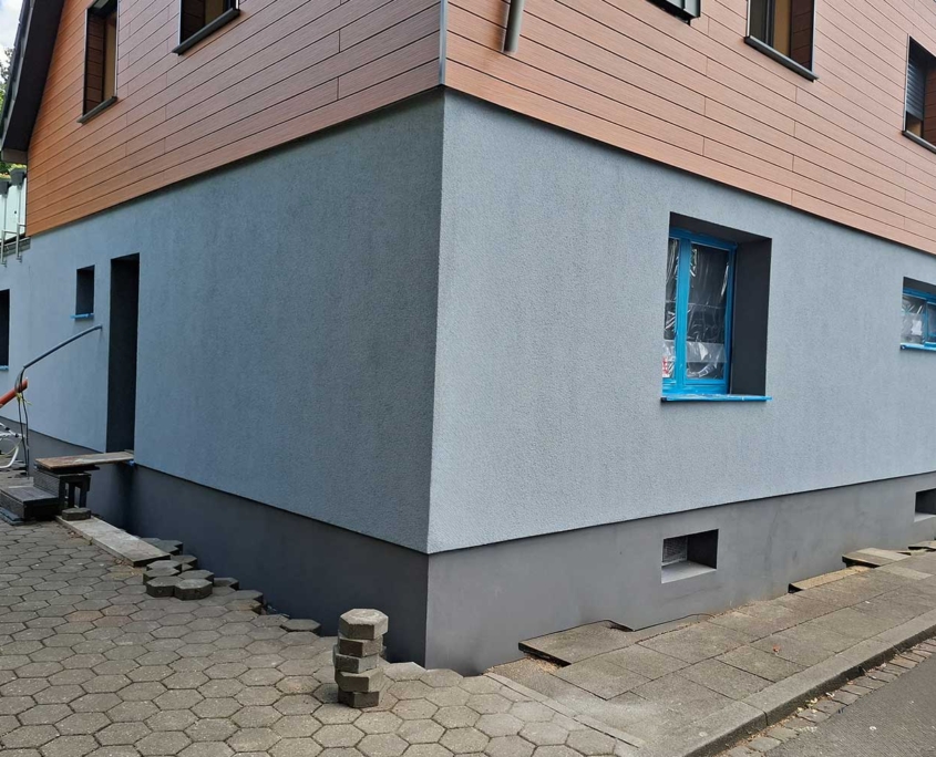Wärmedämmverbundsystem (WDVS) mit hellgrauer Putzfassade und dunklem Sockel – energetische Fassadensanierung durch Malerfachbetrieb Binder