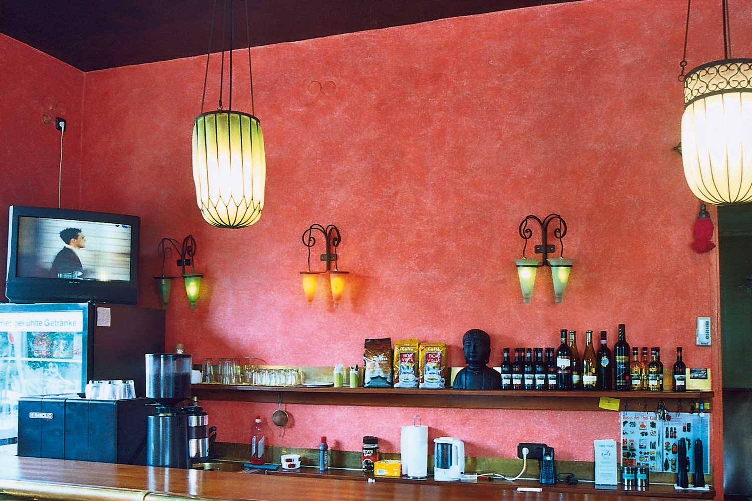Gastronomischer Thekenbereich mit rötlich-korallenfarbener Spachtel- und Wischtechnik, dunkler Decke und dekorativen Wandlampen – professionelle Wandgestaltung gibt es bei Malerfachbetrieb Binder
